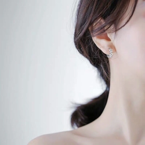 Minimalist silver flower cluster hoop earrings worn by a model in a close-up shot