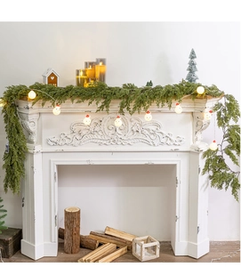 Detail of Christmas artificial cypress garland with snowman LED lights on white fireplace