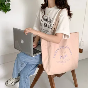 Detail of pink canvas tote bag featuring purple Paris embroidery and flower graphics