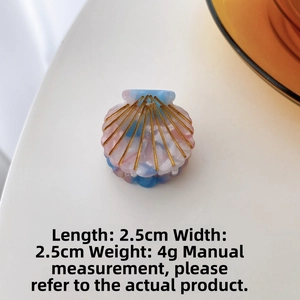 Detail of a shell-shaped acetate hair claw with pastel colors and gold-lined patterns