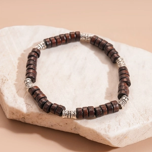 Detailed close-up of ethnic wood beads with engraved silver metal spacers on a stone base