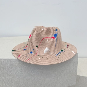 Detailed view of hand-painted colorful splatters on natural woven straw sun hat surface