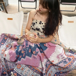 Detail of bohemian geometric woven blanket with tassels in an outdoor camping setting