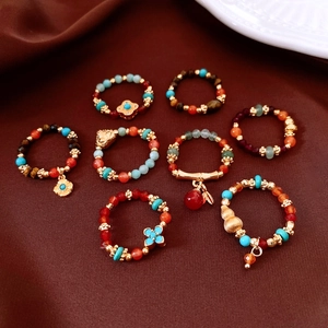 Detail of vintage beaded ring set featuring tiger eye, agate and gold lucky charms