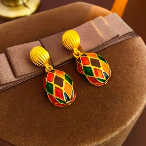 Detail of vintage gold earrings with colorful enamel geometric patterns on velvet gift box