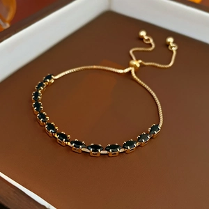 Detail of adjustable gold bracelet featuring elegant black oval gemstones on a display tray