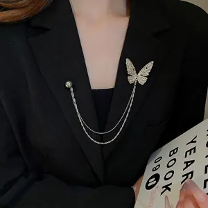 Silver butterfly brooch with tassel chain and grey pearl on black blazer suit lapel