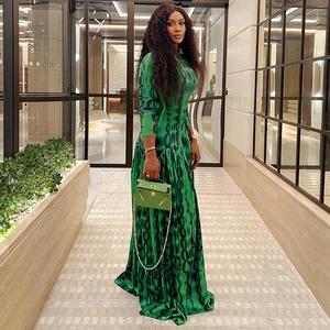 Detail of a green abstract print maxi dress paired with a matching leather handbag