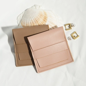 Detail of square PU leather jewelry gift pouches in brown and pink with button closure