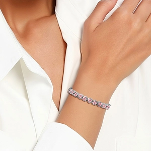 Close-up of a pink heart-shaped zircon bracelet on a wrist with silver-tone plating