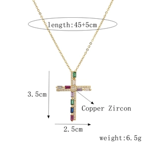 Détail macro du pendentif croix dorée avec zircons colorés et mesures de la chaîne