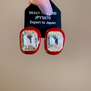 Close-up of geometric square studs in dark red enamel with diamonds and silver pins