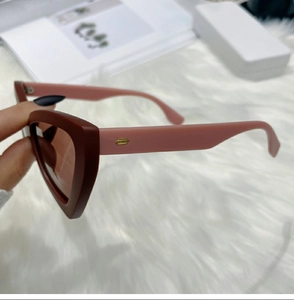 Detailed side view of cat-eye sunglasses with burgundy frames and pink temples