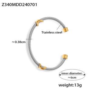 Detailed view of silver stainless steel twisted cable bangle with gold leaf accents