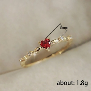 Elegant gold woven ring with a heart-shaped red zircon and dainty white side stones