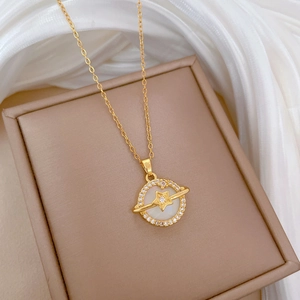 Detailed close-up of golden planet pendant with shell inlay and zircon accents on jewelry box