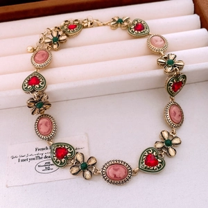 Detailed macro view of vintage gold necklace with pink cameo and green heart charms