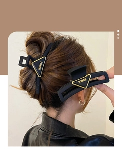 Detail view of black matte hair claw and pin with gold POWER triangle accent on hair