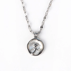 Detailed macro of vintage silver necklace featuring shell inlay and rose engraving