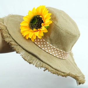 Detail of sunflower decoration and polka dot ribbon on a frayed edge straw sun hat