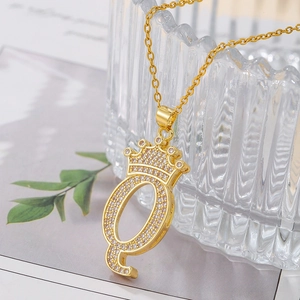 Close-up of a gold-plated crown letter Q pendant necklace encrusted with white zircon stones