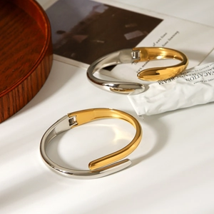 Detailed view of bicolor gold and silver stainless steel cuff on a stylish desk