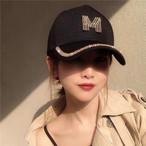 Close-up of golden M-logo and sparkling rhinestones on black cotton baseball cap