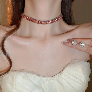Model wearing orange zircon necklace and round stud earrings set in warm lighting