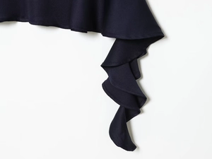 Detail of navy blue ruffled fabric with metal rivet studs on an asymmetric dress