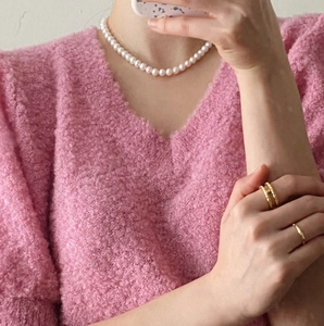 Detail of 925 silver 10mm pearl necklace with vintage gold rings on a pink sweater