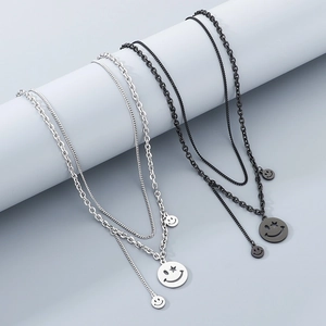 Detail of double-layer silver and black smiley face pendant necklaces on a grey stand