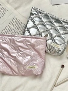 Quilted PU leather cosmetic bags in pink and silver on soft white faux fur background