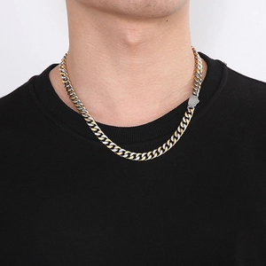 Close-up of dual-tone gold and silver Cuban chain necklace on a male model wearing black