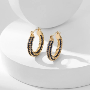 Golden hoop earrings with three rows of micro-paved blue zircons on white pedestal