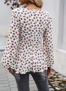 Detail of floral puff sleeve blouse with smocked waist and ruffled hem from back view