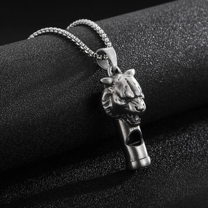 Detailed view of a silver lion head whistle pendant on a black textured background