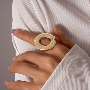 Close-up of a large irregular hammered gold ring on finger with a minimalist design