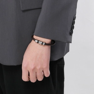 Brown braided leather bracelet with silver magnetic clasp worn with a grey suit