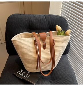 Close-up of beige woven tote bag with brown leather handles and decorative clasp