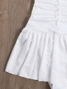 Macro shot of white eyelet embroidery fabric with ruffled hem on wooden background