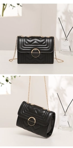Close-up of black quilted shoulder bag with gold chain strap and metal buckle