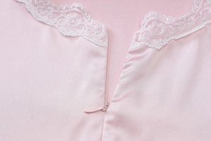 Close-up of pink silk halter dress featuring white lace trim and a hidden zipper