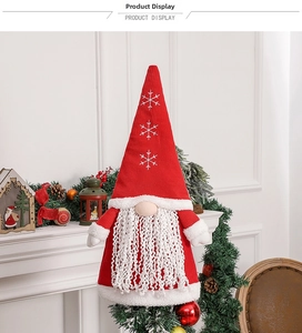 Detail of red knitted Christmas gnome with white snowflake embroidery and plush beard