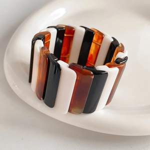 Macro shot of wide geometric resin stretch bracelet with black white and amber tiles