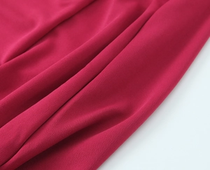 Macro di tessuto a maglia rosso rosa che mostra la texture morbida e il drappeggio