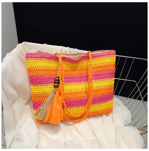 Detail of rainbow striped straw tote bag with decorative wooden bead tassels for beach