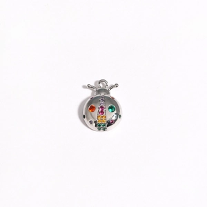 Detailed view of silver ladybug pendant with colorful inlaid gems on white background