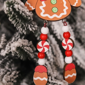 Detail of wooden gingerbread man Christmas tree ornament with beads and snowy background