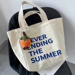 Detail of canvas tote bag with blue summer lettering and a cute orange persimmon charm
