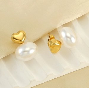 Detail of vintage heart and pearl earrings with gold finish on elegant silk background
